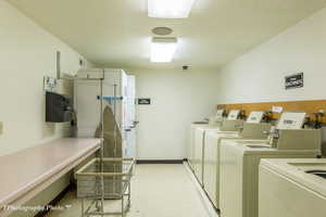 Community laundry room with washing machine and clothes dryer and a textured ceiling