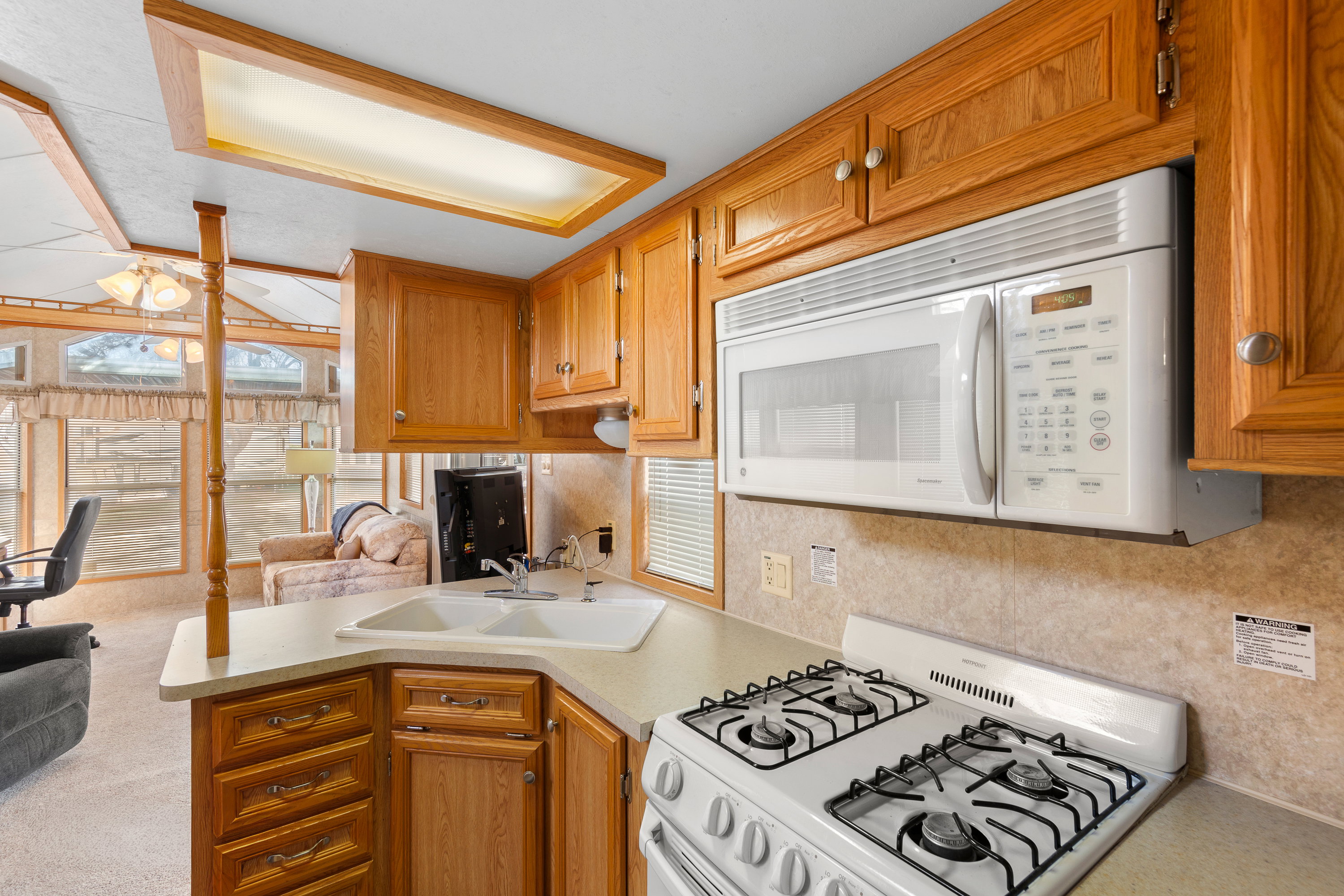 Kitchen featuring white appliances, brown cabinetry, and light countertops