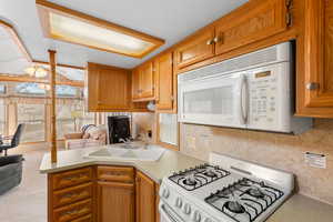 Kitchen featuring white appliances, brown cabinetry, and light countertops