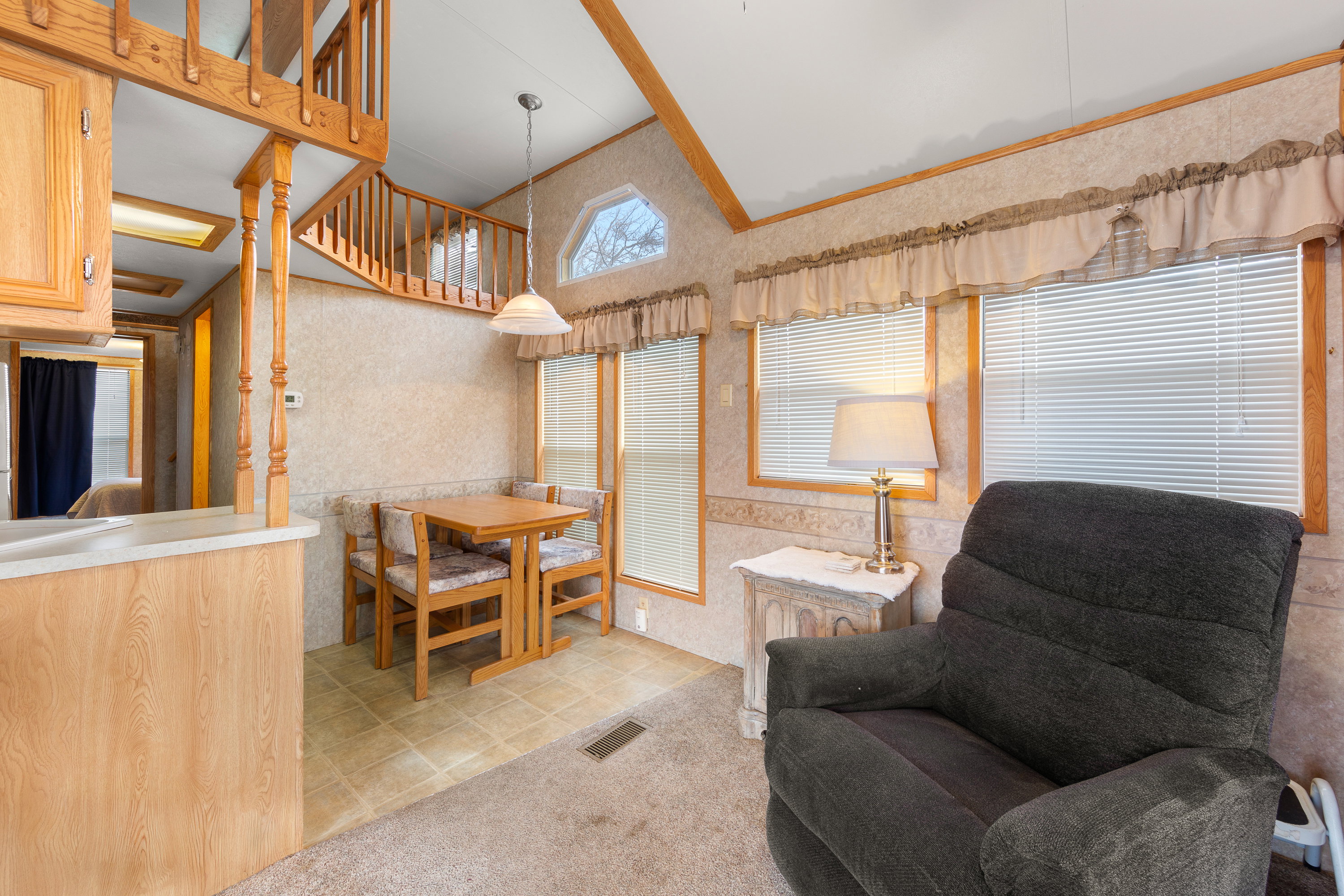 Dining area with wallpapered walls, light colored carpet, and vaulted ceiling
