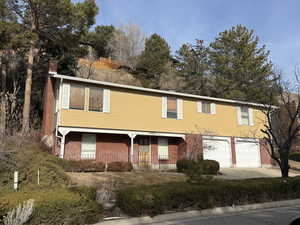 View of front of home with driveway, a chimney, a garage, a porch, and brick siding