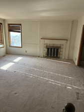 Unfurnished living room with a fireplace, carpet flooring, and ornamental molding