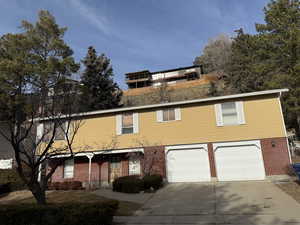 View of front of home with concrete driveway, covered porch, an attached garage, and brick siding