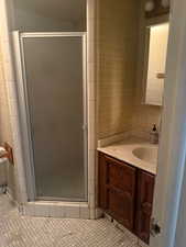 Full bathroom featuring vanity, a stall shower, and light tile patterned flooring