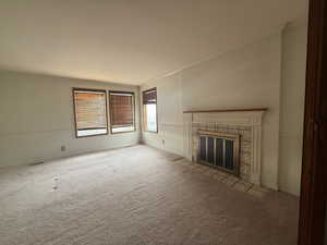 Unfurnished living room featuring a fireplace, carpet flooring, and ornamental molding
