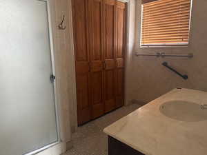 Full bath with vanity, a shower stall, and a closet