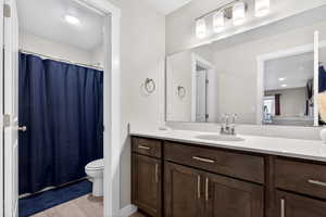 Bathroom with a shower with curtain, vanity, light wood finished floors, and recessed lighting
