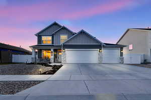 View of front of property featuring board and batten siding, stone siding, a porch, concrete driveway, and an attached garage