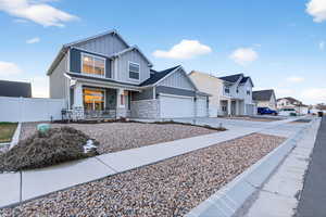 View of front facade featuring board and batten siding, driveway, a porch, and stone siding
