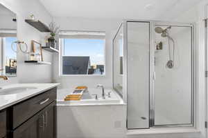 Bathroom featuring a bath, vanity, and a marble finish shower