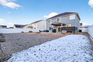 Snow covered property with a fenced backyard, a patio area, and stucco siding