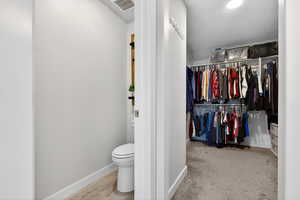 Bathroom with a walk in closet and light colored carpet