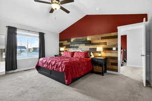 Bedroom with an accent wall, wooden walls, lofted ceiling, carpet flooring, and ceiling fan