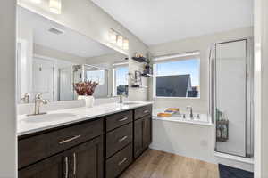 Bathroom with a marble finish shower, double vanity, a garden tub, and light wood-style flooring