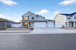 View of front of home featuring a porch, board and batten siding, stone siding, driveway, and a garage