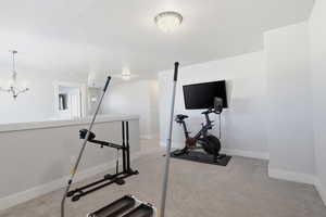 Workout room with light colored carpet and a chandelier