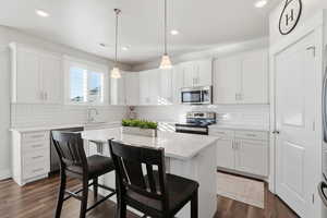 Kitchen with a kitchen bar, white cabinetry, a center island, stainless steel appliances, and recessed lighting