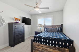 Bedroom with light colored carpet and a ceiling fan