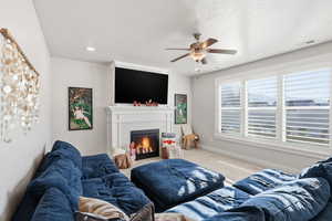 Living room featuring a fireplace, carpet floors, and ceiling fan