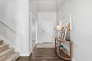 Entrance foyer featuring stairs, dark wood-type flooring, and a towering ceiling