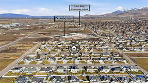 Aerial view of property and surrounding area featuring nearby suburban area and a mountainous background