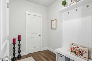Mudroom featuring dark wood-type flooring and baseboards