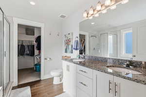 Bathroom with a spacious closet, a stall shower, double vanity, recessed lighting, and wood tiled floors