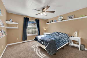 Bedroom featuring carpet flooring, ceiling fan, and a textured ceiling