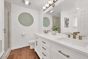 Full bath featuring dark wood-type flooring, double vanity, and a shower stall