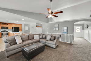 Living room featuring recessed lighting, a ceiling fan, a wainscoted wall, light colored carpet, and vaulted ceiling
