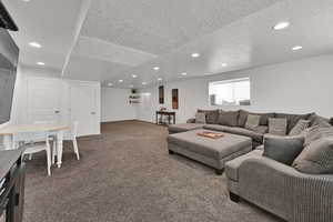 Carpeted living area featuring a textured ceiling and recessed lighting