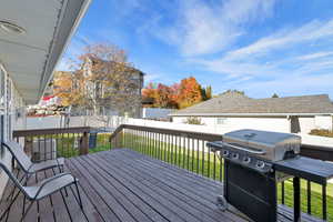 Wooden terrace with a fenced backyard and a grill