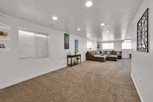 Living room with recessed lighting, light colored carpet, and a textured ceiling