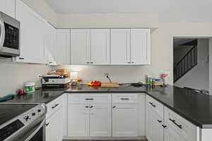 Kitchen with appliances with stainless steel finishes, white cabinets, and a peninsula