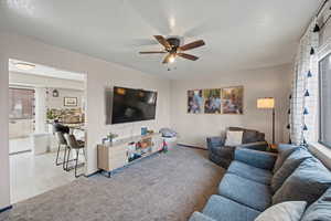 Living area with light colored carpet and a ceiling fan