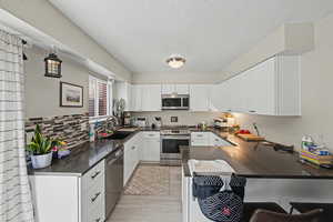 Kitchen featuring stainless steel appliances, white cabinets, light wood-type flooring, and a peninsula