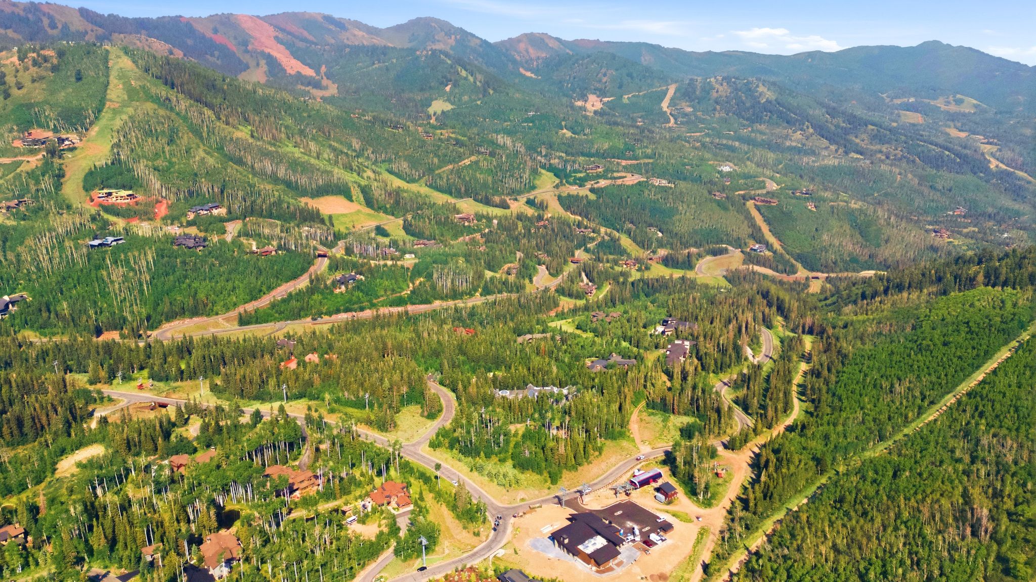 Expansive mountain landscape featuring dense evergreen forests and winding roads