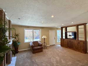 Light and spacious living room with elegant carpet, a textured ceiling, fireplace, and recessed lighting