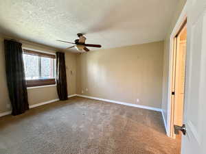 Primary bedroom conveniently located and featuring carpet flooring, ceiling fan, and a textured ceiling