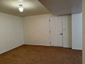 Carpeted downstairs family room with a textured ceiling and baseboards