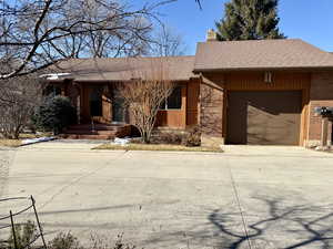 View of front of this charming home located in a quiet cul-de-sac with brick siding, concrete driveway, covered porch, and an attached garage
