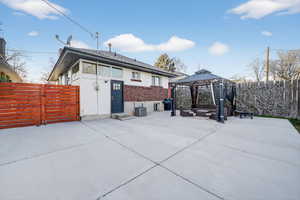 Rear view of house featuring a fenced backyard, a gazebo, a patio area, brick siding, and a gate