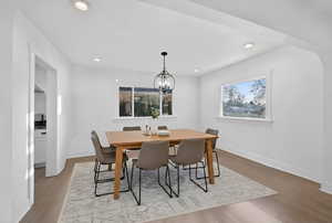 Dining room with arched walkways, light wood finished floors, and hanging lights