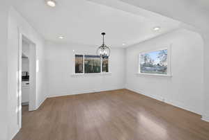 Unfurnished dining area with light wood finished floors, a chandelier, recessed lighting, and arched walkways