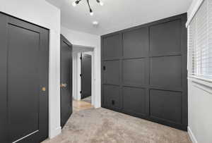 Unfurnished bedroom with a decorative wall, light colored carpet, and a closet