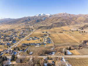 Aerial view of property and surrounding area with mountains, rural landscape, and nearby suburban area