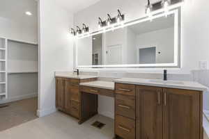 Bathroom featuring double vanity, a walk in closet, and light colored carpet