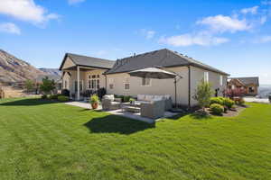 Enhanced staged back yard (Landscaping not included) Rear view of property featuring a lawn, stucco siding, a patio area, outdoor lounge area, and a mountain view