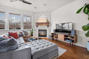 Living room featuring dark wood-type flooring, a fireplace, a ceiling fan, and recessed lighting