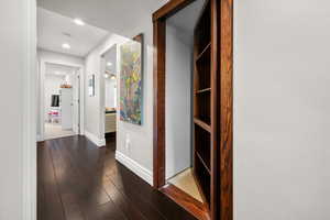Corridor with dark wood-style flooring and recessed lighting